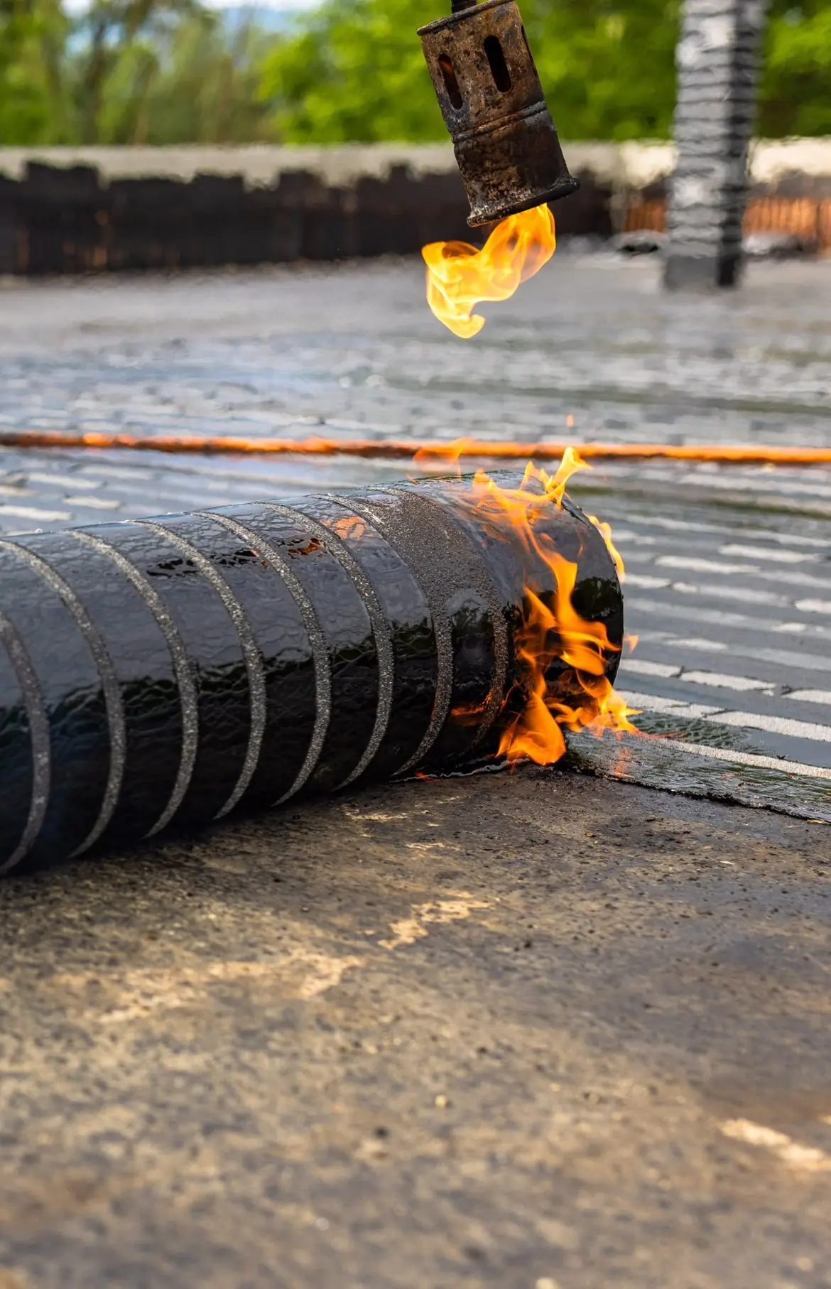 Pose d'une membrane bitume sur un toit terrasse Étancheur soudant une membrane bitumineuse au chalumeau sur un toit plat